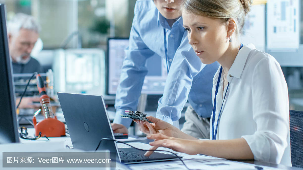 女計算機科學(xué)家將電路板連接到她的筆記本電腦并開始編程。她在先進(jìn)技術(shù)實驗室工作。